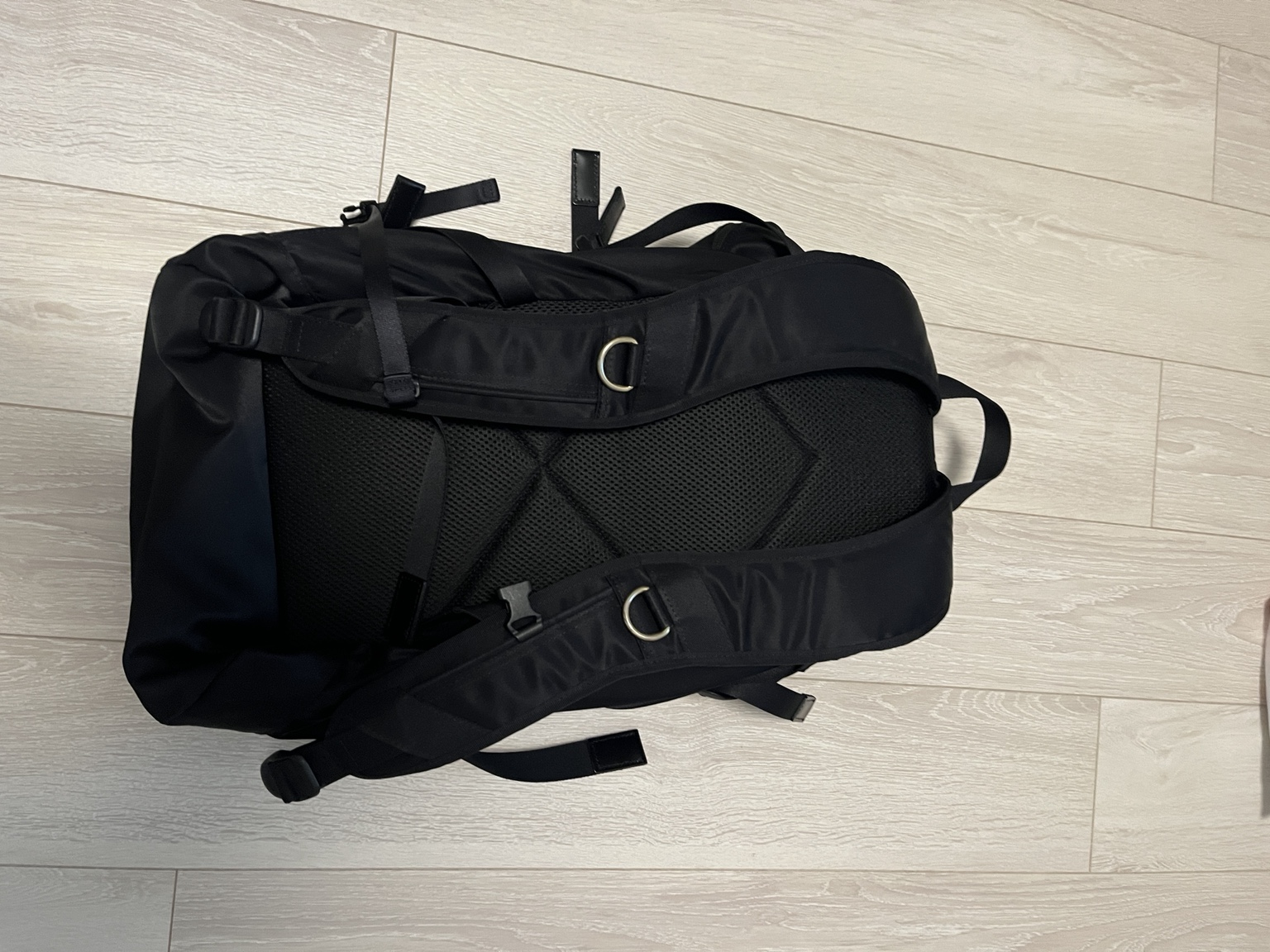 黒いバックパックのメッシュ状の背面と、Dリング付きショルダーストラップ。